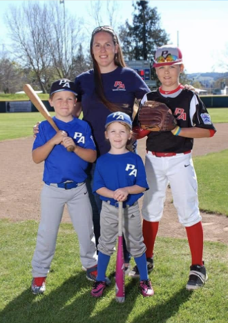 Student Alum Kristi Lozinto standing with children in baseball uniforms